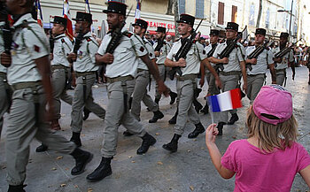 photo défilé militaire du 14 juillet avec petite fille en rose qui agite un drapeau Français