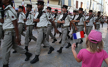 photo défilé militaire du 14 juillet avec petite fille en rose qui agite un drapeau Français
