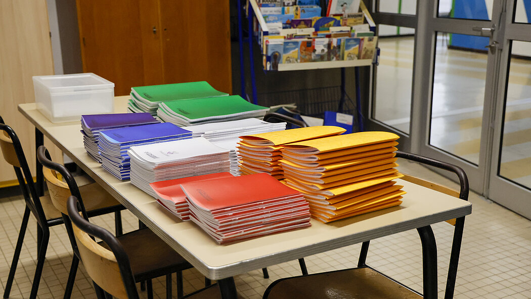 une table avec des piles de livres et cahiers jaune, rouge, beu, vert