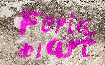 texte feria de l'art tagué à la bombe rose sur mur gris