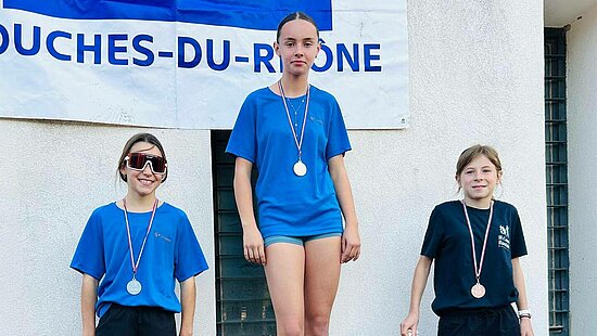 Trois jeunes filles sur un podium de sport