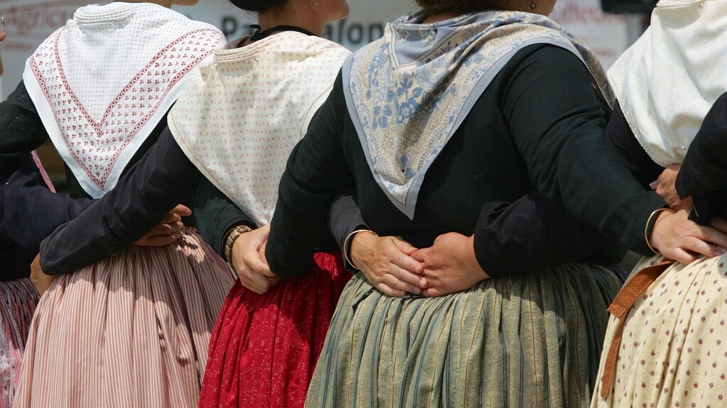femmes en tenues provençales de dos qui se tiennent par la taille - foulards et robes colorées