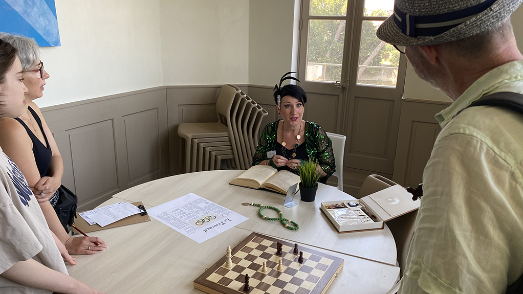Une femme assise à une table et trois personnes debout qui l'écoutent