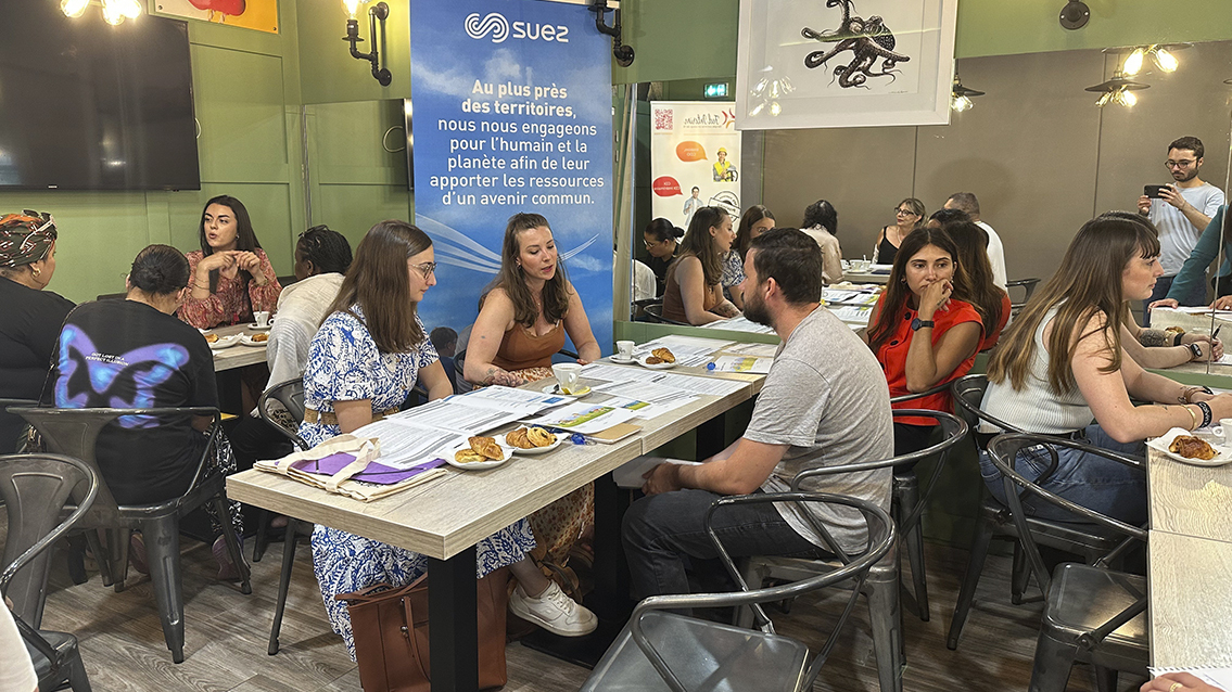 Des personnes, femmes et hommes, assis autour de plusieurs tables