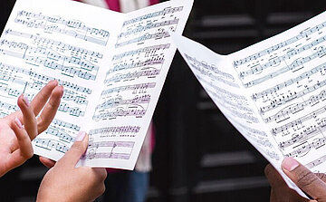 Photo de main avec partition de musique chorale en répétition 