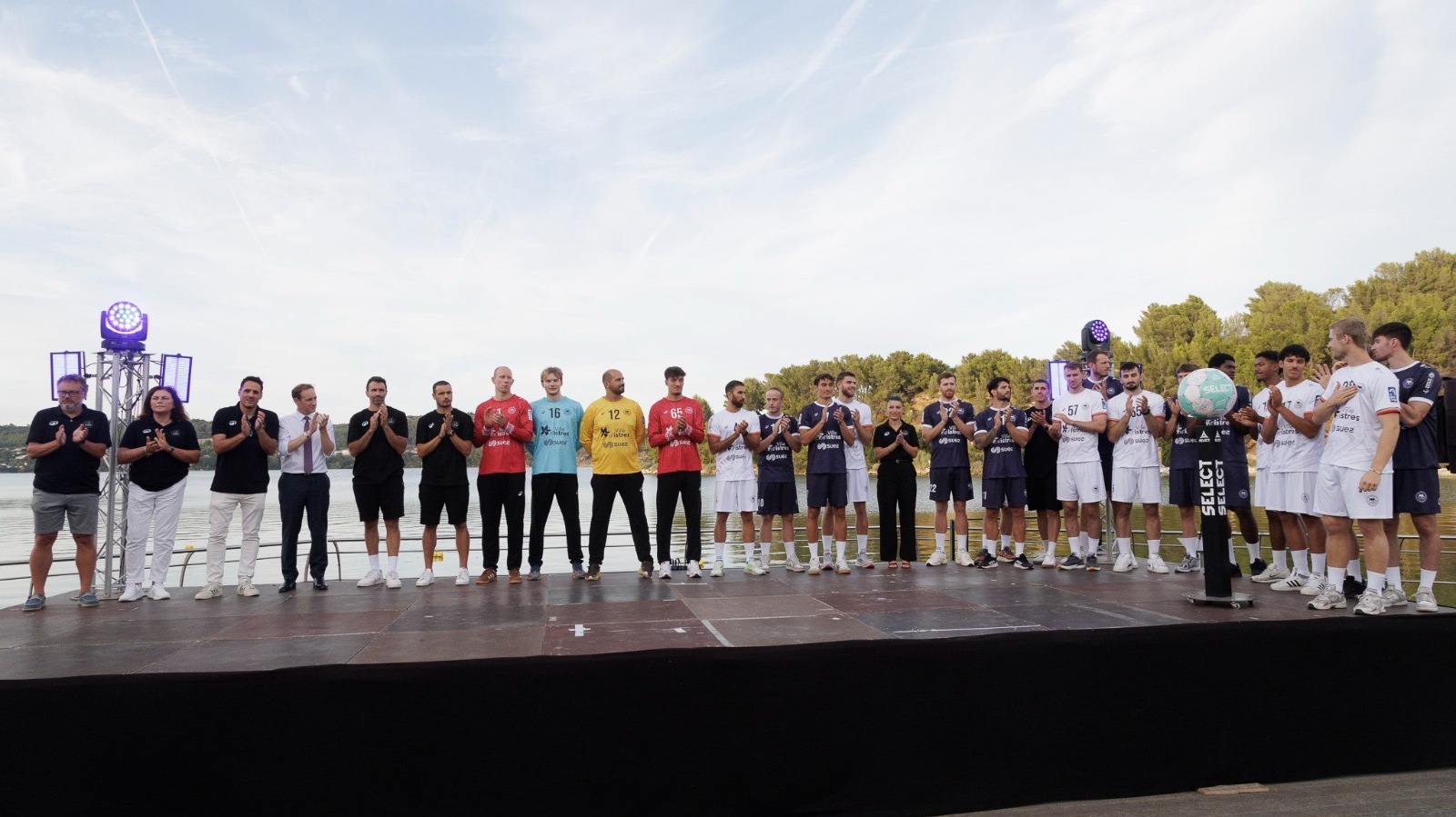 les joueurs de l'Istres Provence Handball et leur staff, alignée et applaudit sur une scène en plein air, au bord de l'étang de l'Olivier, lors de la présentation officielle de l'équipe