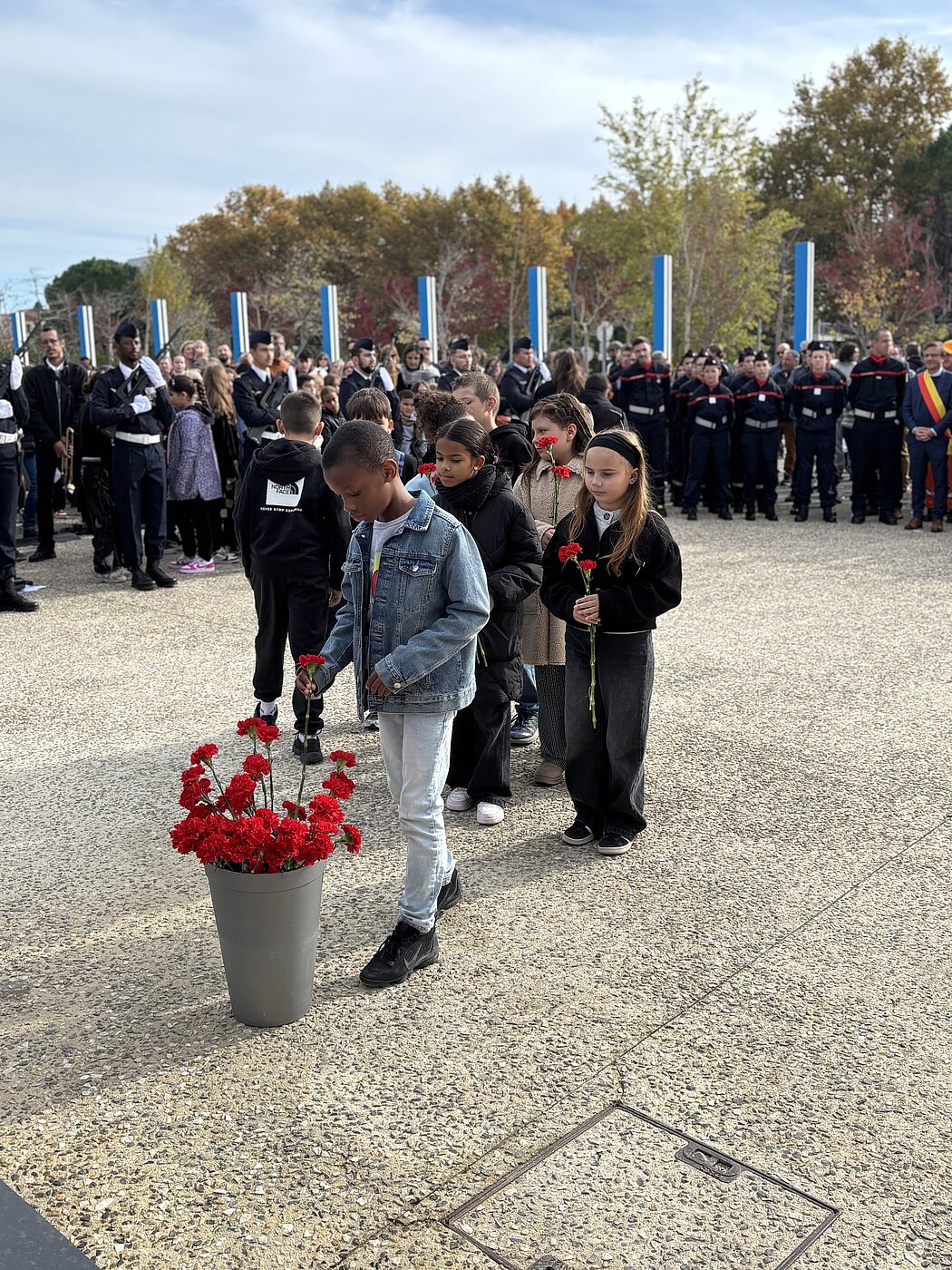 Les enfants déposent des oeillets rouge