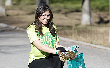 Photo jeune fille au tee shirt vert Istres propre qui ramasse des déchets 