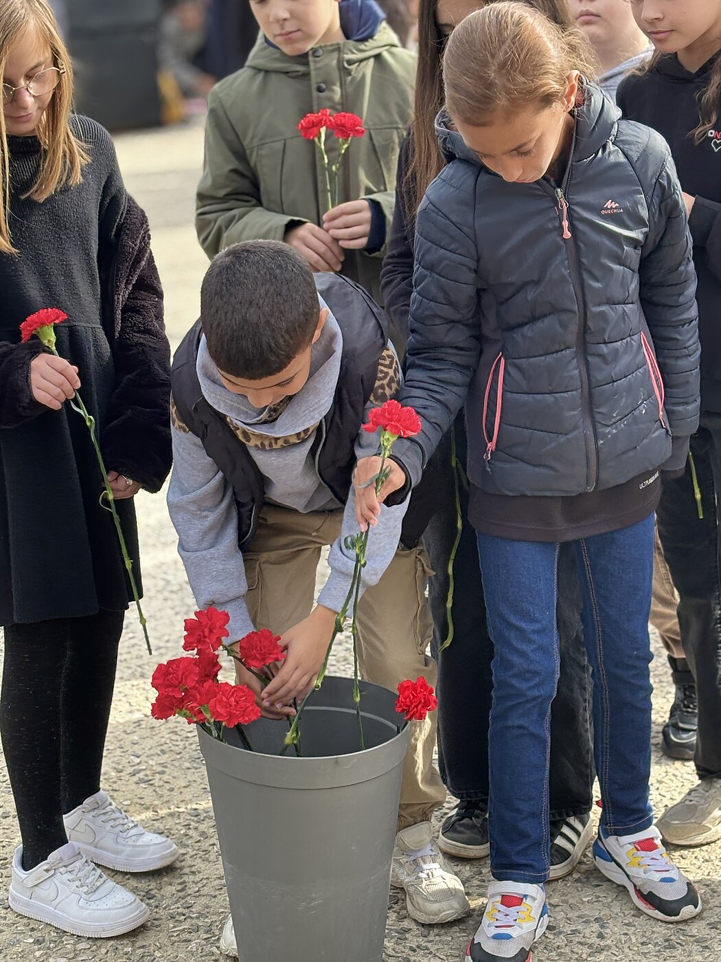 Les enfants déposent des oeillets rouge
