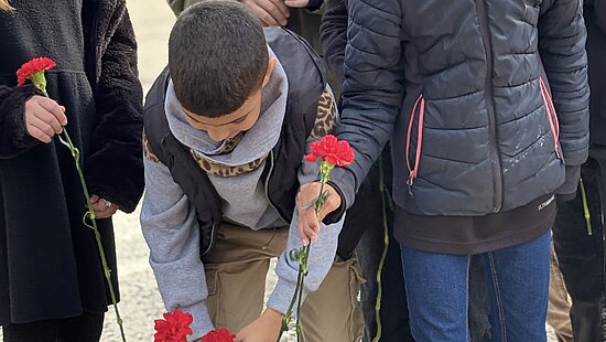 Les enfants déposent des oeillets rouge