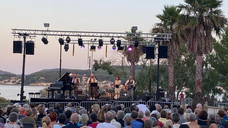 Concert de jazz sur la plage sable palmier foule assise et debout