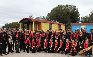 photo de Harmonie municipale étoile d'istres groupe de musciens avec instruments en habits noirs et rouges devant roulottes