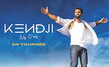 Photo de KENDJI GIRAC On voit une personne debout, photographiée en plan moyen, avec les bras ouverts de chaque côté du corps. Elle porte un débardeur blanc, une chemise blanche ouverte par-dessus, et un jean bleu.  La personne a les cheveux foncés et une barbe. Le visage est visible et orienté vers l’avant.  Le fond de l’image représente un ciel bleu avec des nuages.  À gauche de l’image, du texte est visible :  « KENDJI » écrit en grandes lettres blanches  en dessous : « Nos 10 ans »  plus bas : « EN TOURNÉE » écrit en lettres jaunes  L’ensemble de l’image est lumineux, avec un contraste entre les vêtements clairs et le fond bleu.