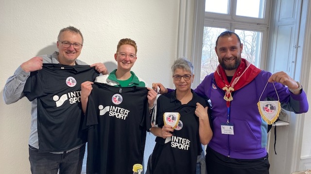 Quatre personnes montrent des tee shirts de sport et un fanion