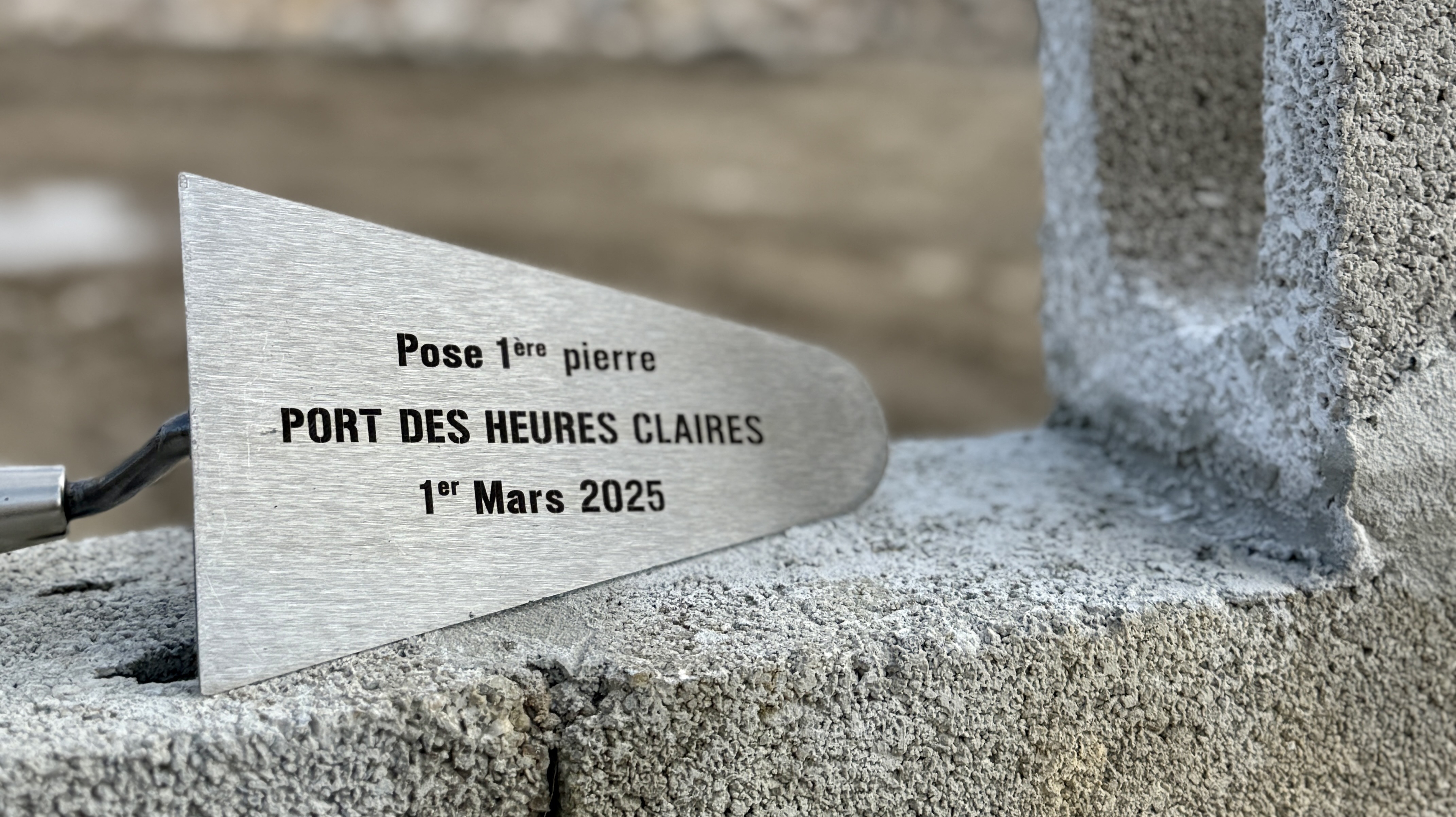 une truelle de maçon avec l'inscription pose de la premiere pierre du port des heures claires