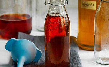 photo de bouteille de sirop rouge orange et entonnoir bleu