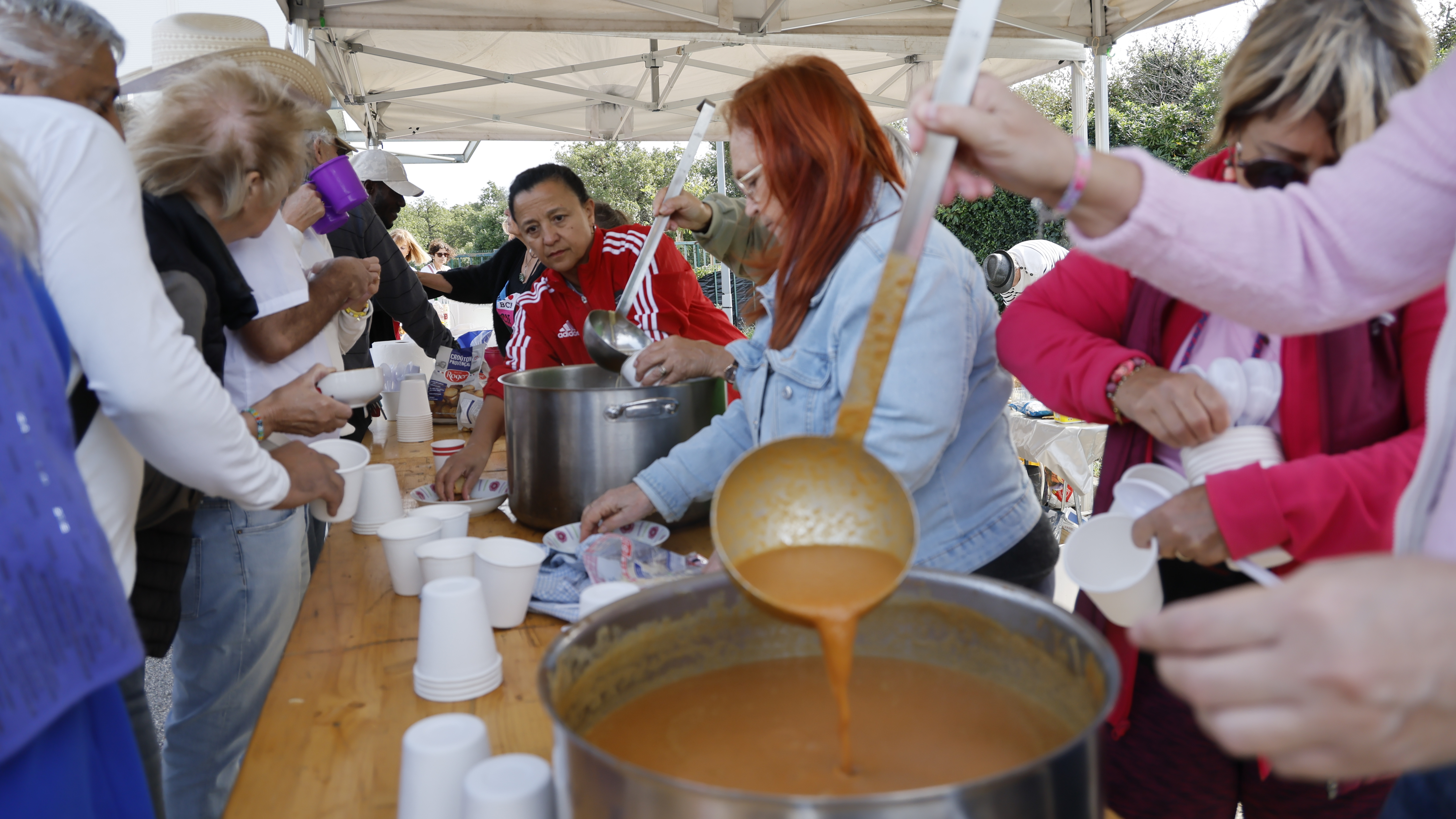 Une marmitte de soupe et des personnes autour
