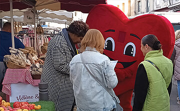 photo mascotte coeur avec gens sur un marché