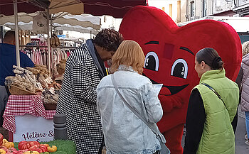 photo mascotte coeur avec gens sur un marché