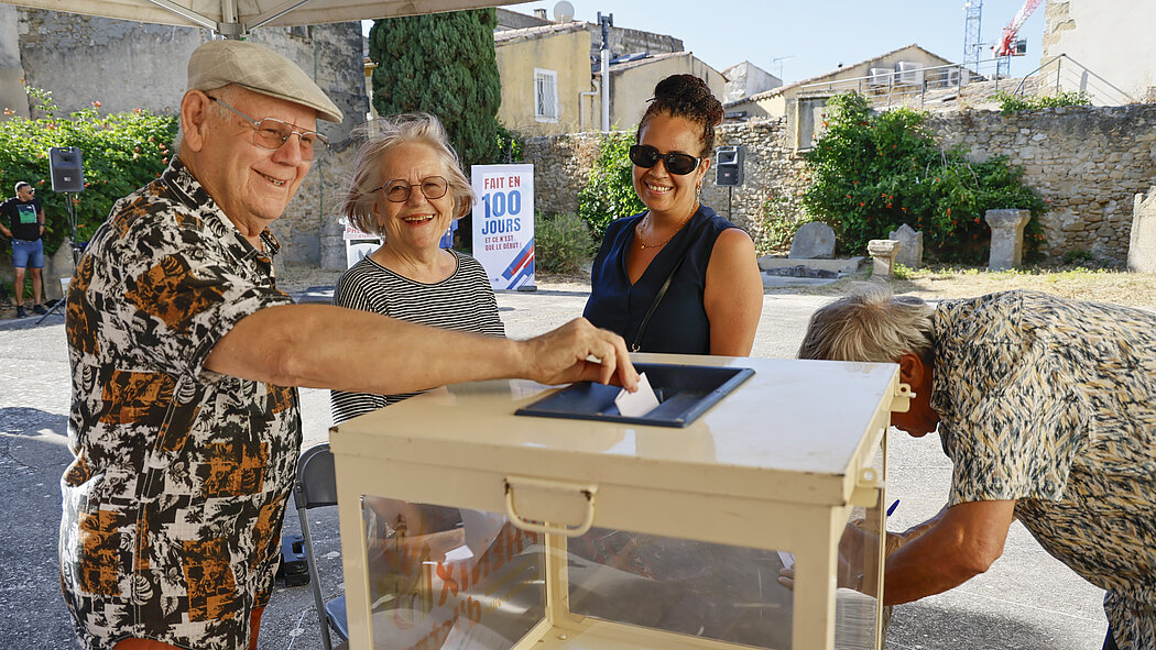 Un homme met dans un urne sa participation à la boîte à idée pour redynamiser le centre ville