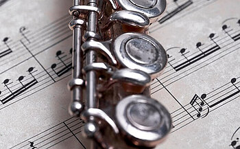 photo de flûte traversière  posée sur une partition de musique 