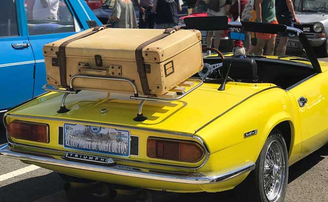 photo de voiture ancienne décapotable jaune avec valise sur le coffre