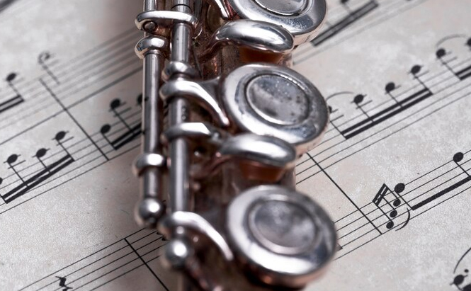 photo de flûte traversière  posée sur une partition de musique 