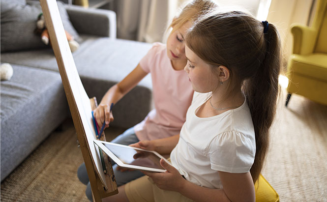 Enfant qui dessine sur un tableau et un autre qui tient une tablette